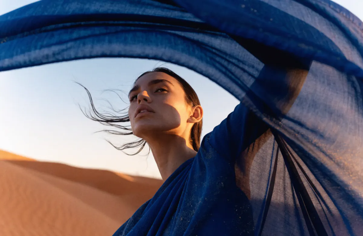 Generated fashion portrait of a woman walking through desert dunes